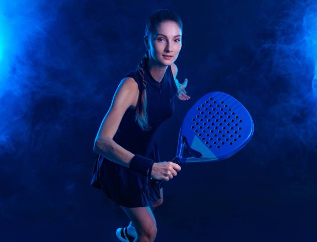 Padel tennis player with racket. Girl teenager athlete with racket on court with neon colors. Sport concept. Download a high quality photo for the design of a sports app or betting site